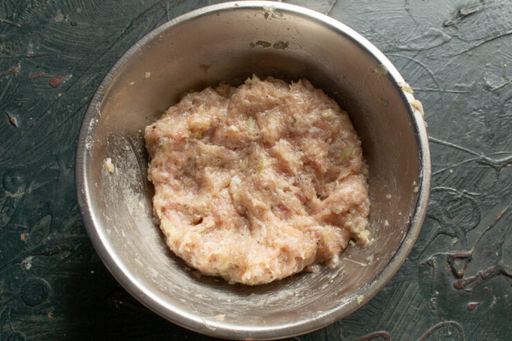 Minced meat ready for shaping Seasoned minced meat with onions in a metal mixing bowl