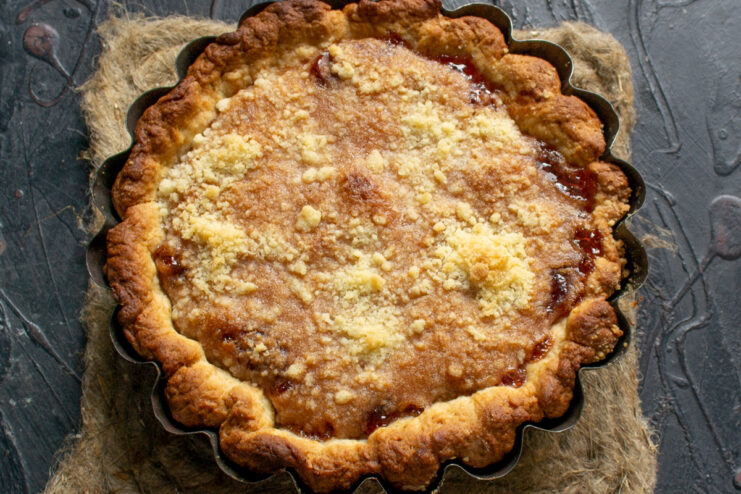 Baked strawberry pie cooling in the pan Freshly baked golden strawberry jam pie resting in a baking pan on a dark surface.