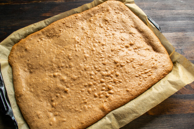 Taking out the baked sponge cake Freshly baked chocolate sponge cake resting on a baking sheet.