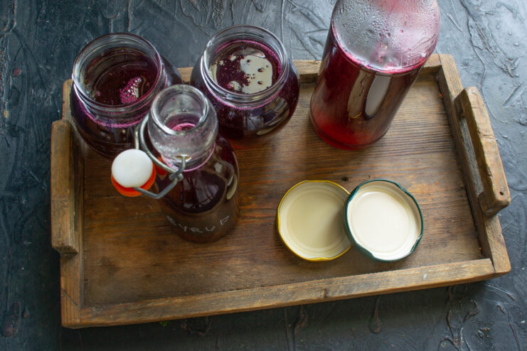Storing raspberry syrup Finished raspberry syrup in bottles on a wooden tray