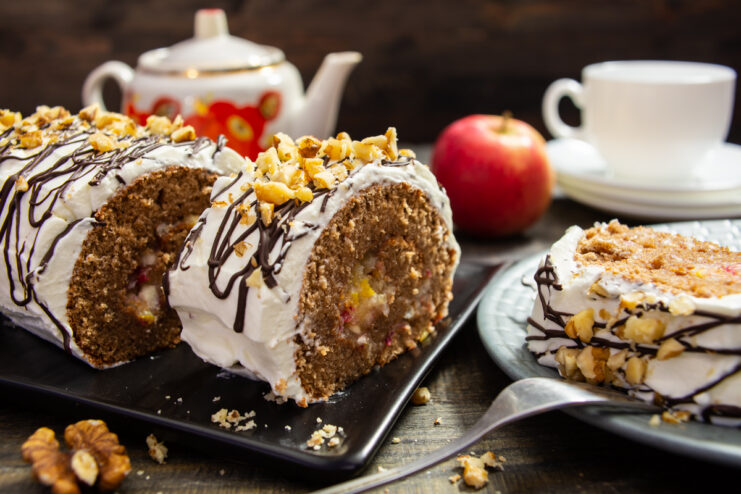 Finished chocolate roll with fruit filling and sour cream frosting, decorated with chocolate and nuts.