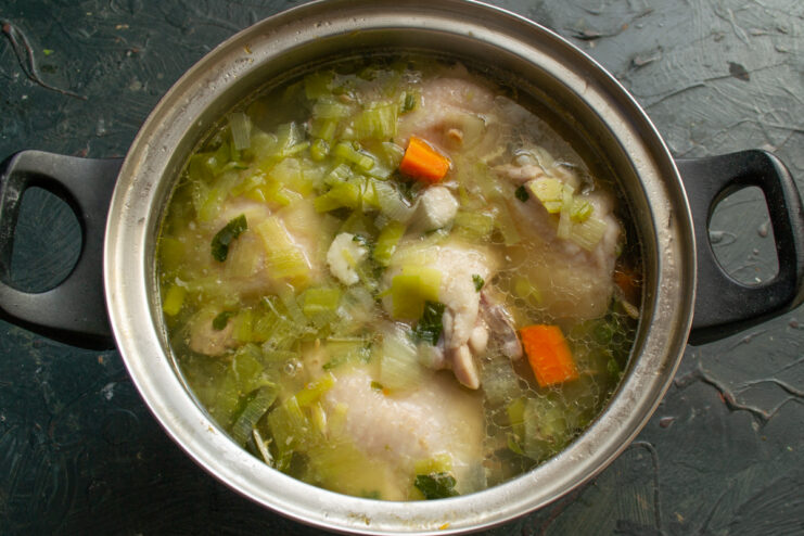 The finished chicken broth Golden chicken broth with vegetables resting in a pot