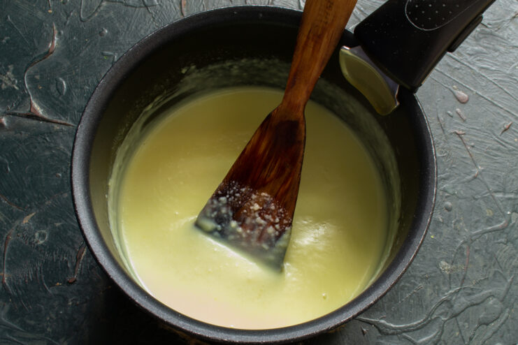 Stirring the sauce until creamy Stirring thick creamy vanilla sauce in a saucepan over low heat