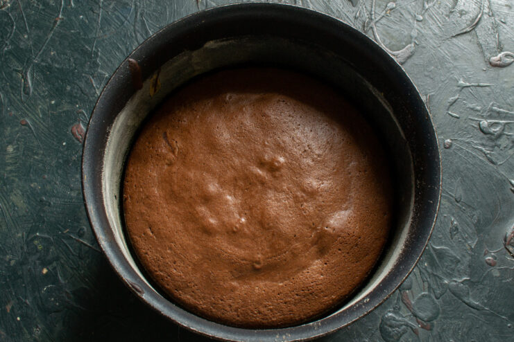 Sponge cake fresh from the oven Baked chocolate sponge cake resting inside a round baking pan