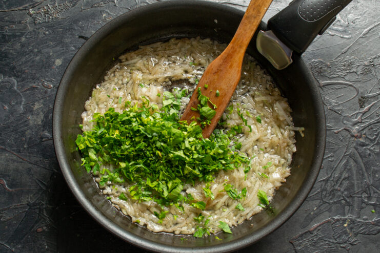 Adding fresh herbs Fresh chopped parsley cooking with onions in a skillet