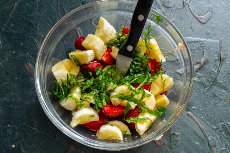 Adding Fresh Mint To The Bowl Finely chopped fresh mint sprinkled over the sliced fruit