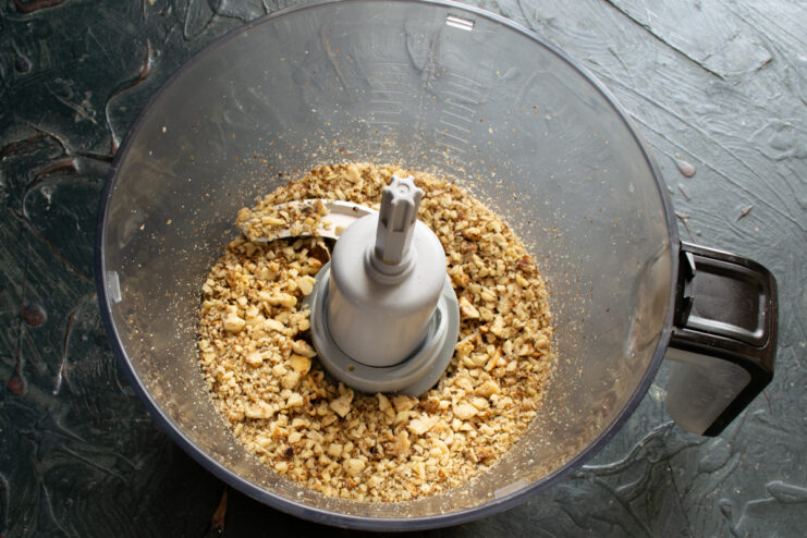 Grinding toasted walnuts Finely ground toasted walnuts inside a food processor bowl