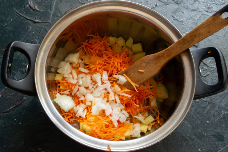 Adding Onion to the Vegetable Mix Chopped white onion mixed with vegetables in a pot