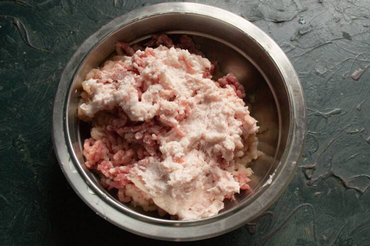 Adding fatback to the mince Ground pork fatback layered on top of the minced meat