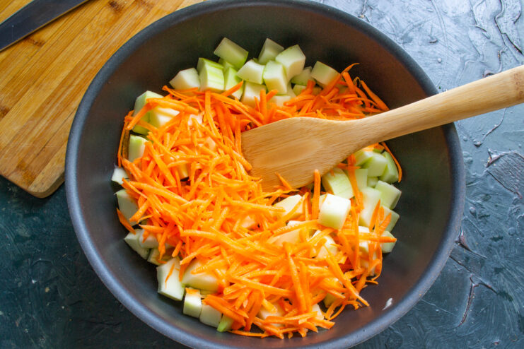 Diced zucchini and grated carrots in a wide pan