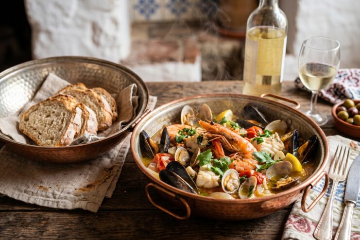 Steaming seafood mix including shrimp and mussels served in a traditional copper cataplana pot
