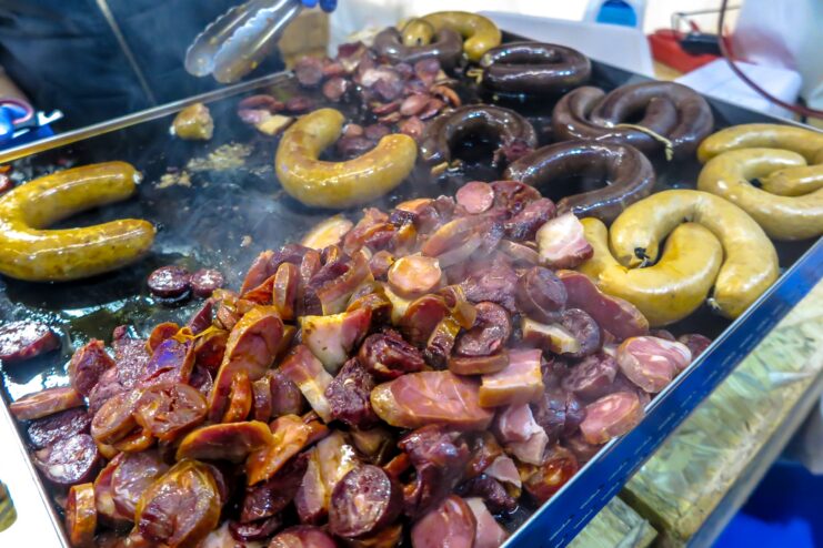 Traditional Alheira and various Portuguese smoked sausages roasting on a hot grill