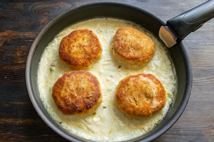 Baking the patties Chicken patties braising in sauce inside a skillet