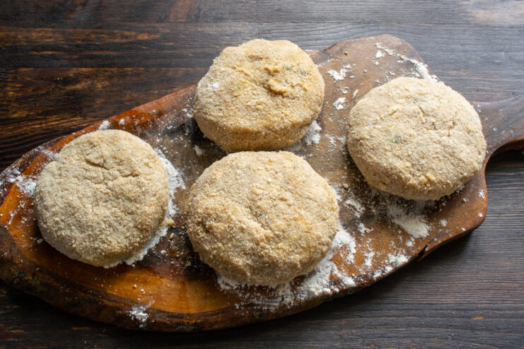 Final breading Breaded chicken patties on a wooden cutting board