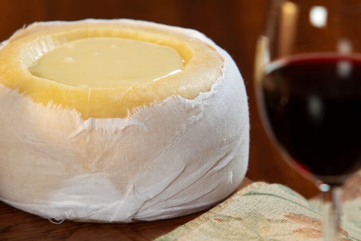 Creamy Queijo da Serra sheep cheese with the top rind removed, served with a glass of red wine