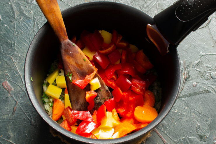 Adding sweet bell pepper Diced red bell pepper added to the vegetable pot
