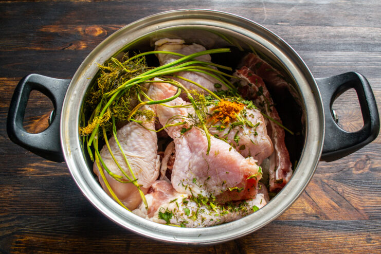 Adding Spices To The Pot Chicken and ribs in a pot with turmeric and herbs