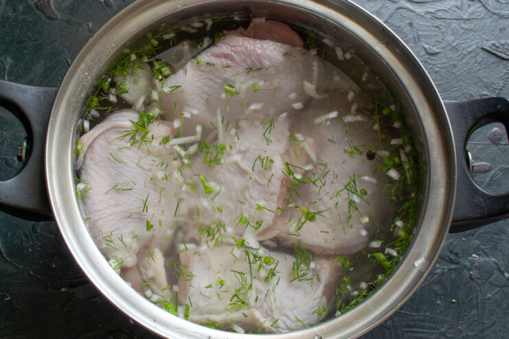Pouring water over the chicken Chicken in a pot being covered with cold water.