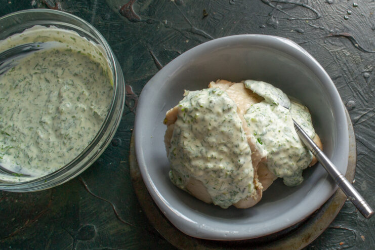 Dressing the chicken with sauce Chicken pieces on a plate drizzled with thick sour cream sauce.