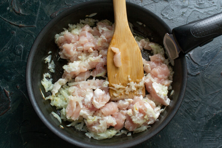 Cooking the filling Cooking diced chicken and onions in a frying pan