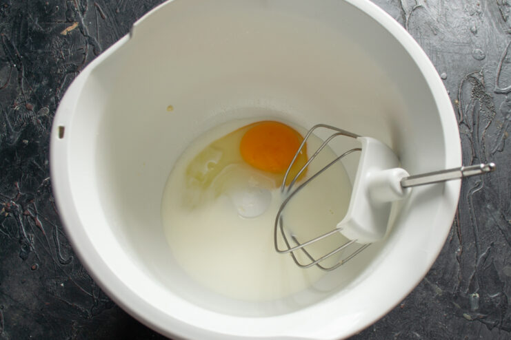 Mixing egg and milk for the dough Raw egg and milk in a white mixing bowl ready for whisking.