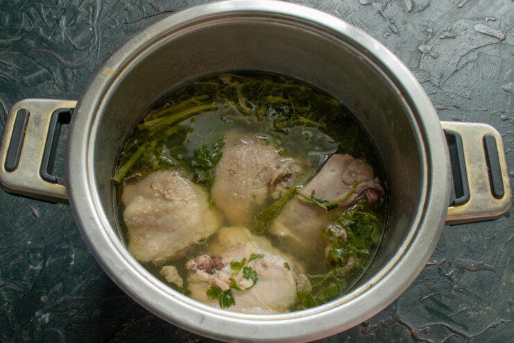 Boiling Chicken Meat Chicken thighs boiling in a pot with parsley and onions