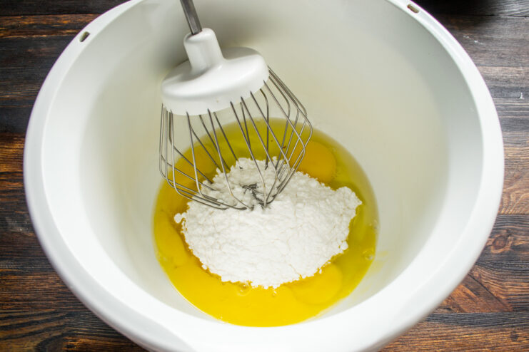Combining eggs and powdered sugar Raw eggs and powdered sugar in a stand mixer bowl before whipping.
