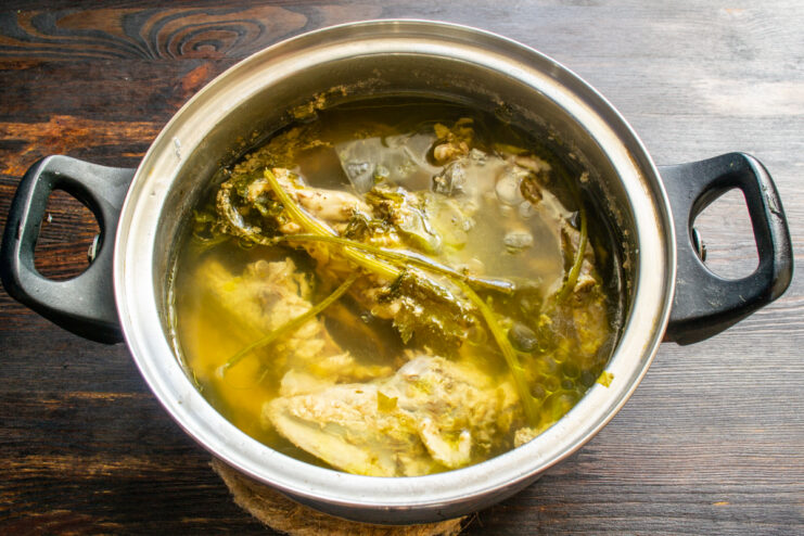 Chicken broth with vegetables and herbs simmering in a pot