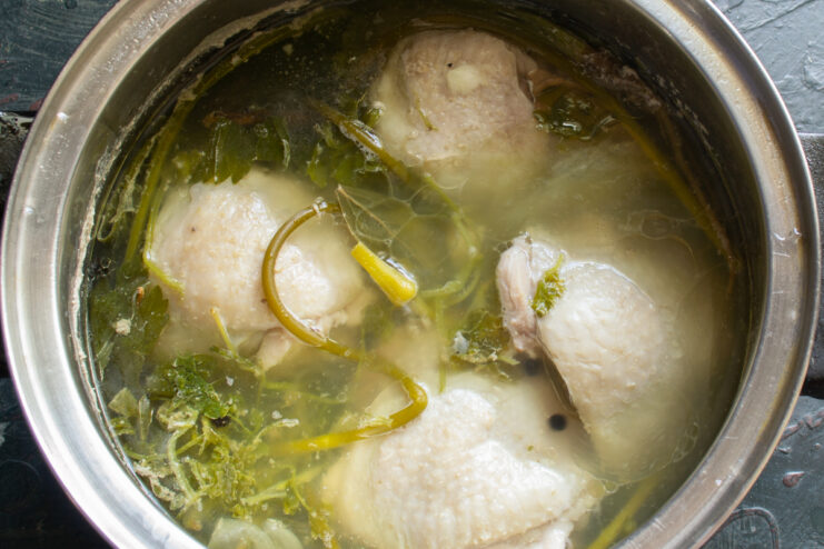 Rich homemade chicken broth Rich homemade chicken broth simmering with aromatic herbs and garlic scapes