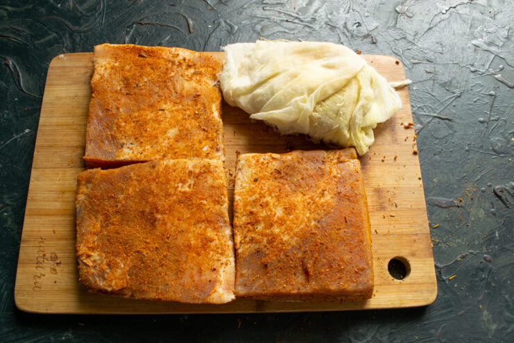Preparing to wrap Spice-coated pork fat sitting next to folded cheesecloth ready for wrapping