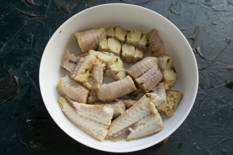 Arranging the Fish Deboned hake pieces arranged tightly in a white baking dish.
