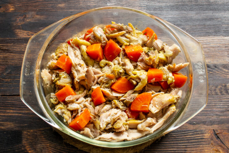 Assembling Aspic In The Dish Chicken pieces and diced carrots arranged in a glass dish
