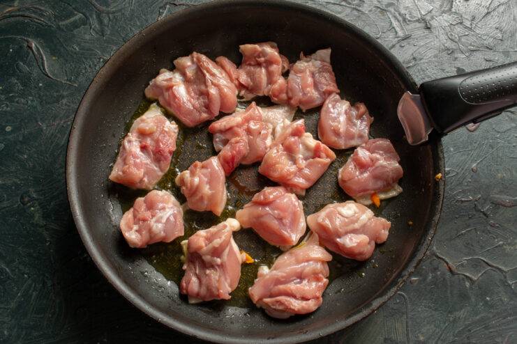 Searing skin-on chicken thigh pieces in a hot skillet