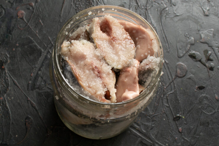 Packing fish tightly into a jar Salt-coated herring packed tightly into a wide-mouth glass jar