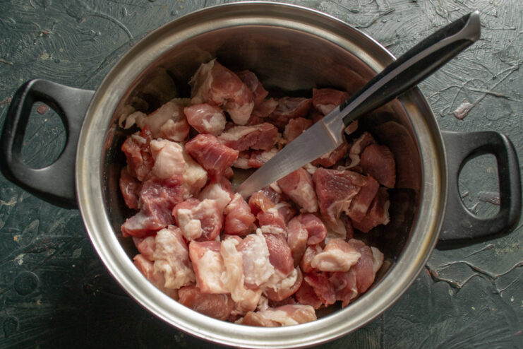 Dicing the meat Cubed raw pork meat inside a cooking pot