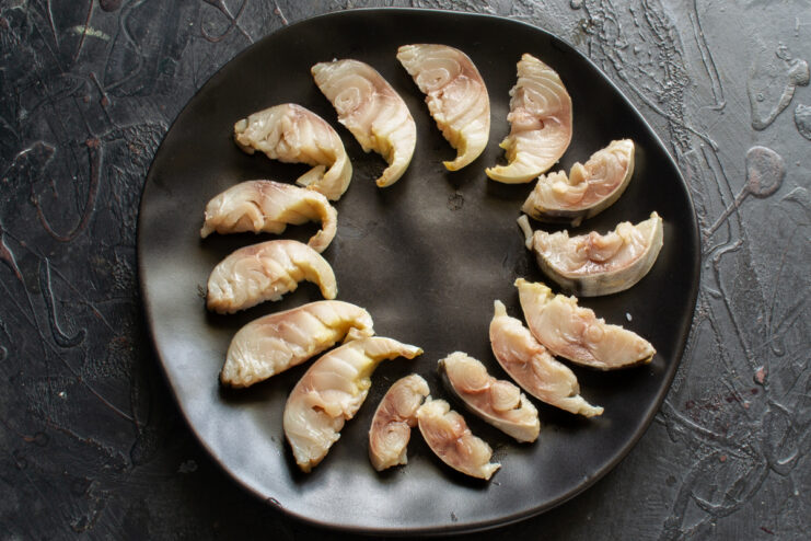 Plating The Mackerel Slices Mackerel slices arranged in a circle on a black plate