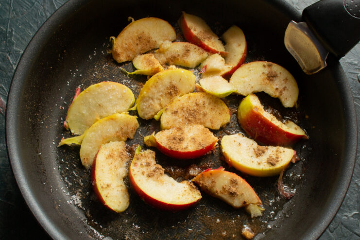Caramelizing Apples With Cinnamon Sliced apples simmering with cinnamon and butter in a skillet