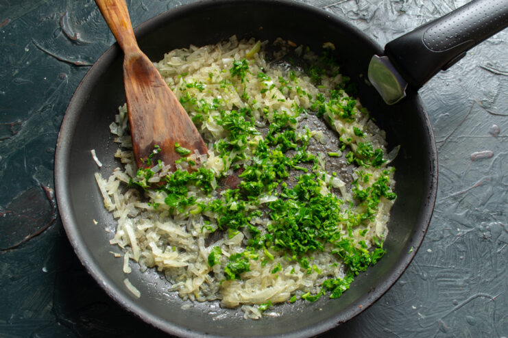 Adding Fresh Herbs Mixing chopped fresh parsley with sautéed onions