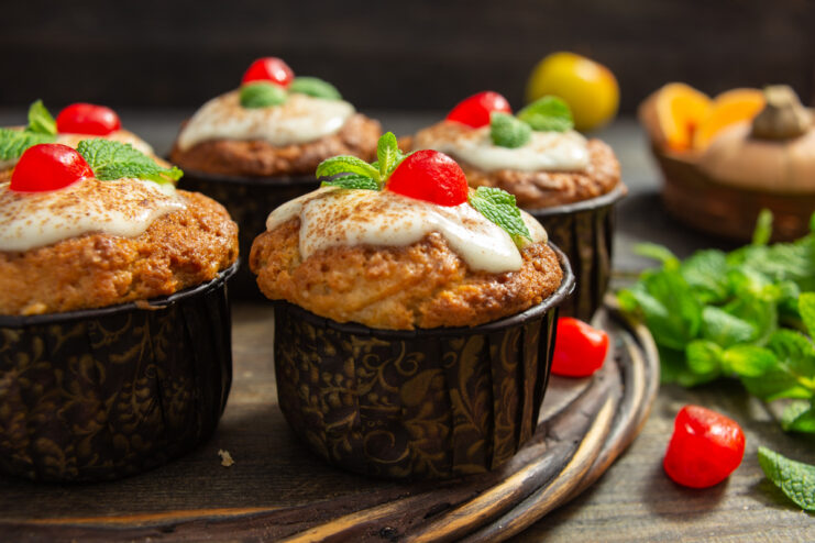 Pumpkin apple muffins garnished with sour cream frosting and a dried cherry.