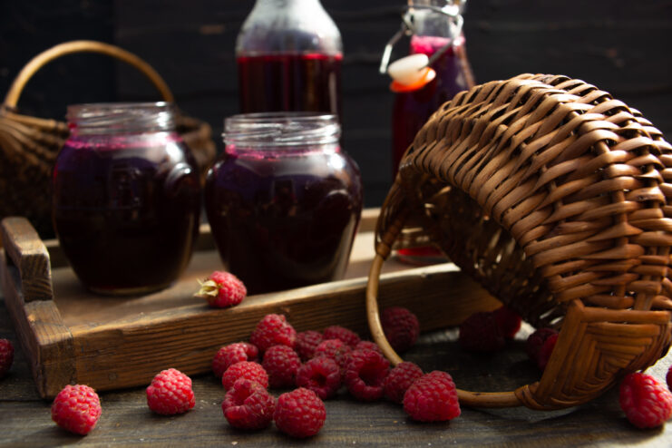 Winter raspberry syrup in jars alongside fresh raspberries