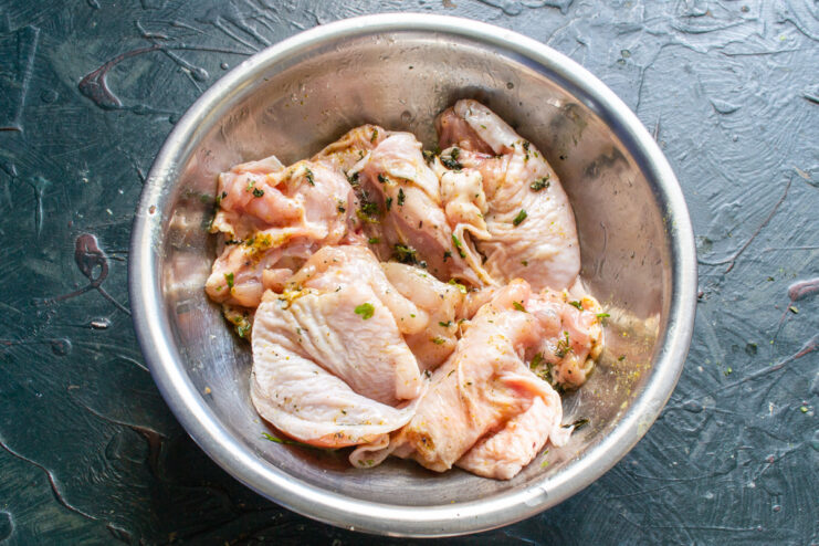 Mixing chicken with minced garlic and olive oil in a bowl