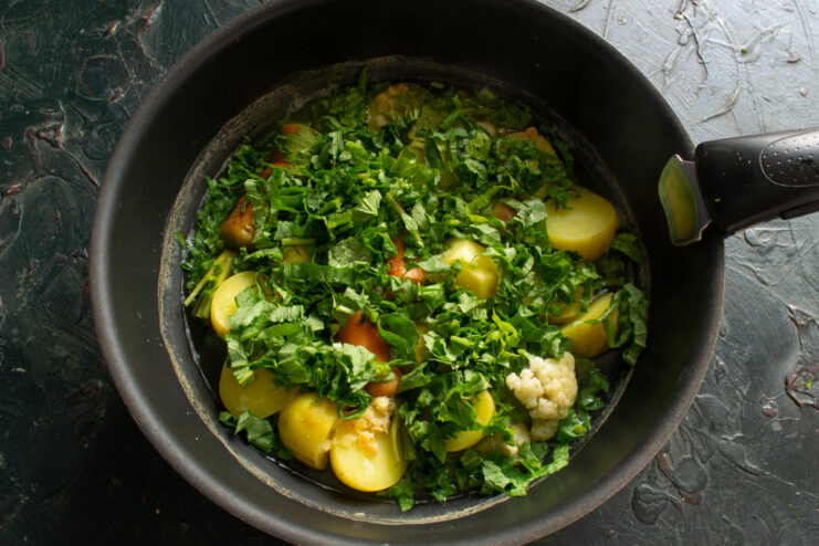 Adding spinach to the soup Finely chopped fresh spinach leaves added to a pot of simmering soup