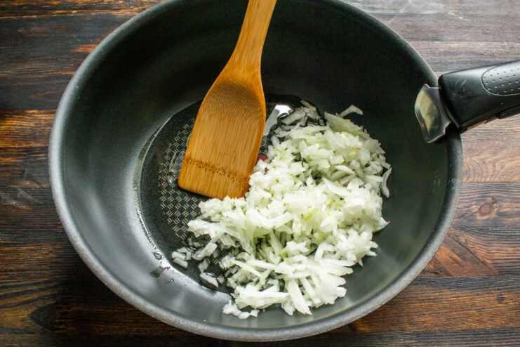 Sauteing the onion Finely chopped onion sauteing in a pan stirred with a wooden spatula