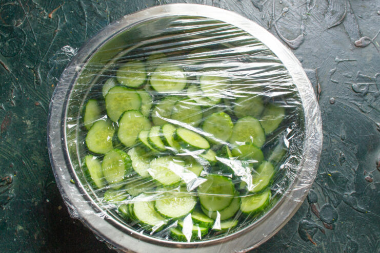Cucumbers Covered with Plastic Wrap Metal bowl with sliced cucumbers covered with plastic wrap