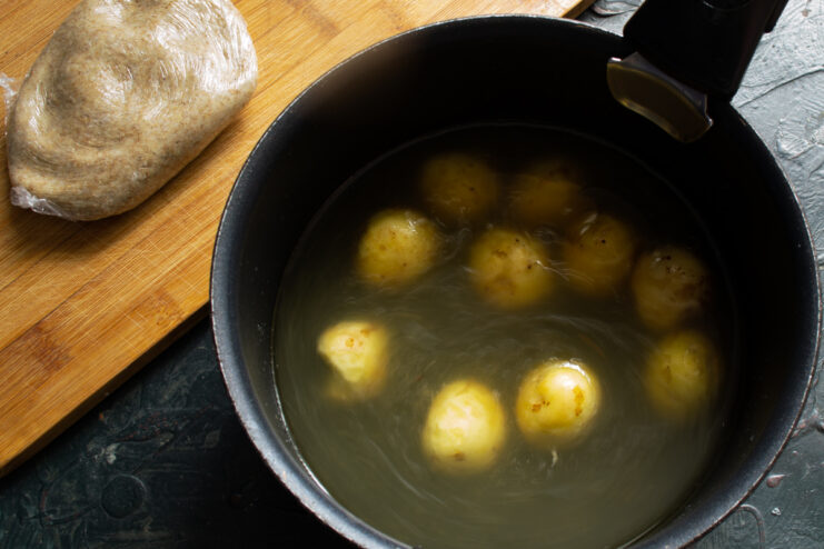 Boiling the new potatoes Scrubbed new potatoes boiling gently in a pot of homemade chicken broth