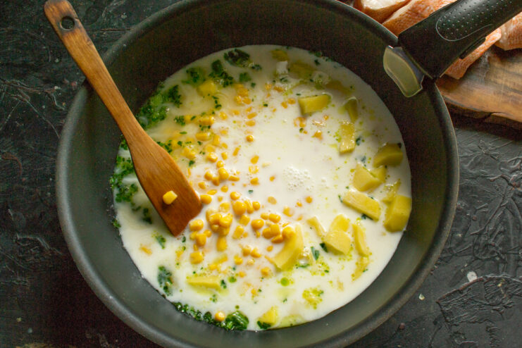 Building the Creamy Broth Milk and water poured into a pot over potatoes and corn
