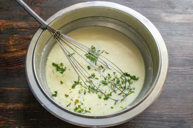 Making the milk sauce Milk mixed with flour and herbs in a bowl with a whisk
