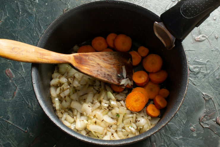 Adding Carrots Adding carrots to onions in a pot