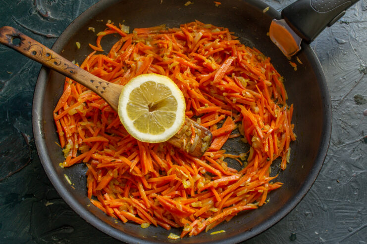 Simmering the Marinade Carrots and a slice of lemon simmering gently in a frying pan.