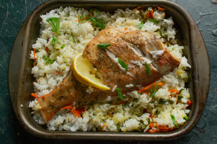 Serving the Baked Sea Bass Baked sea bass and rice garnished with a lemon wedge and fresh herbs